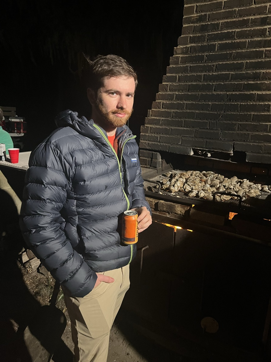 Ledyard beside the brick grill at night with a tray of oysters roasting